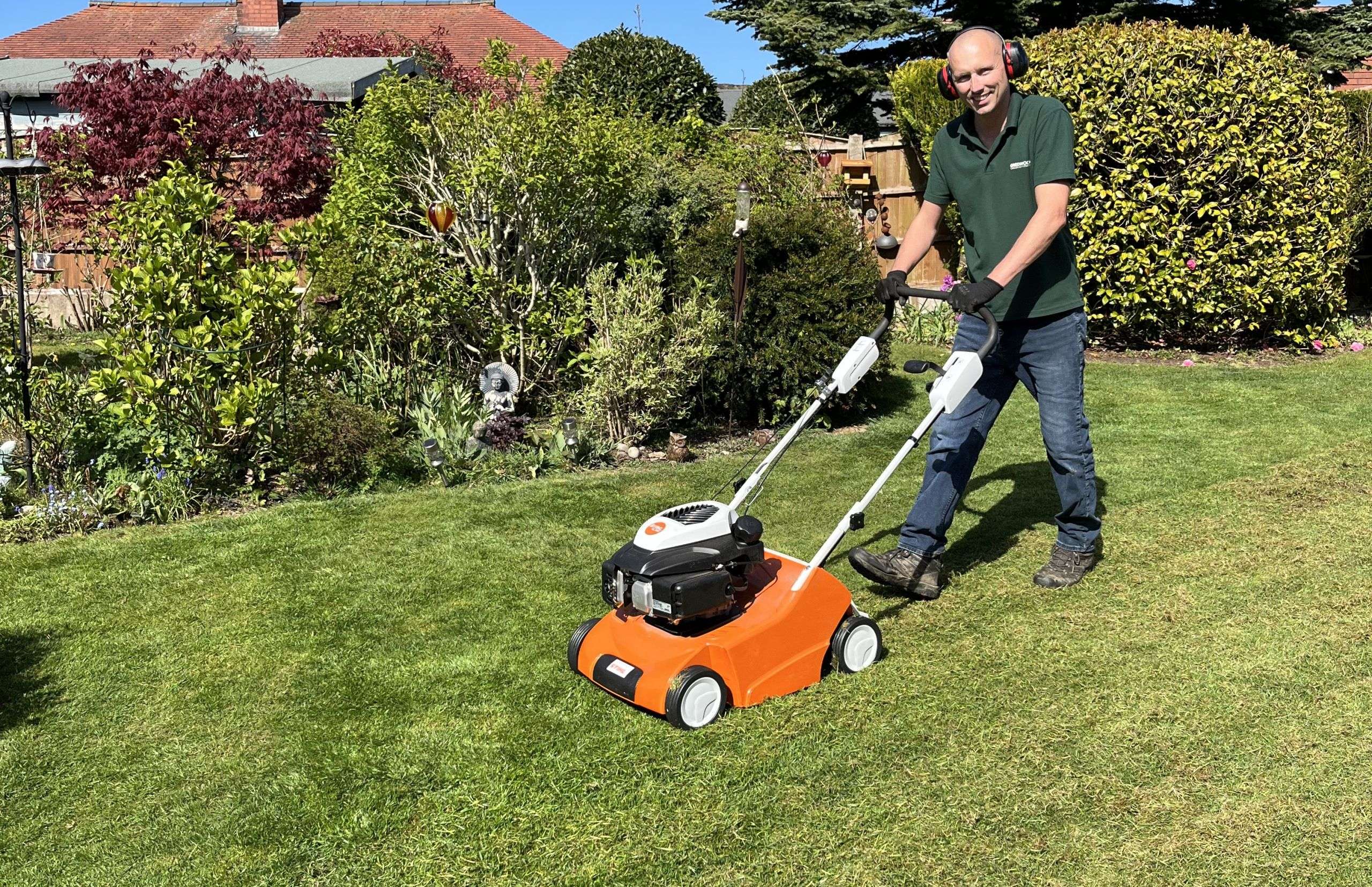 Professional garden maintenance including lawn scarifying to remove thatch and moss from a domestic lawn in Horwich.